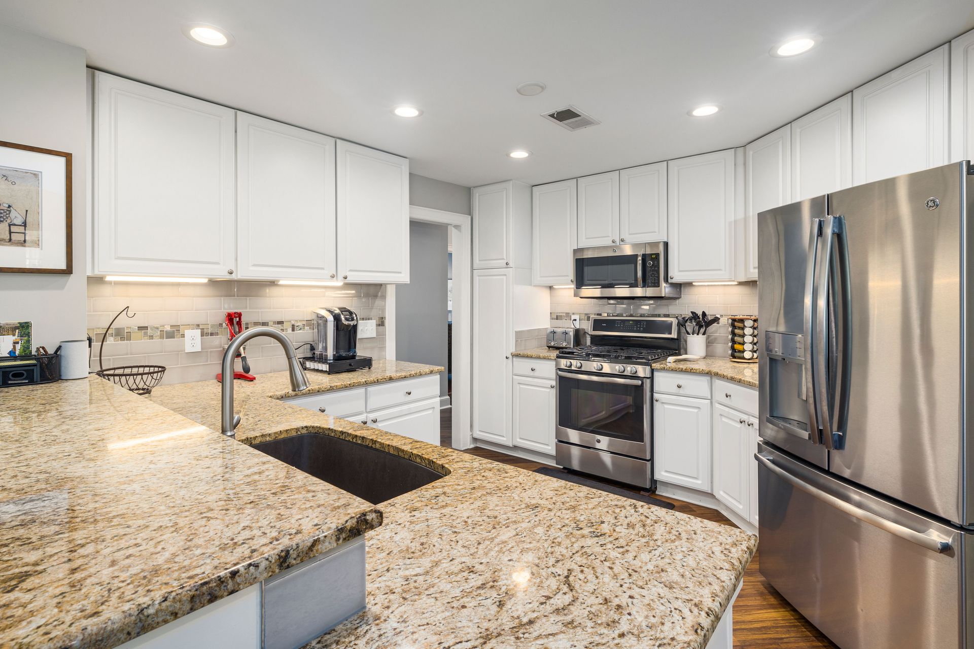 Stylish modern kitchen featuring granite countertops, stainless steel appliances, and white cabinetry.